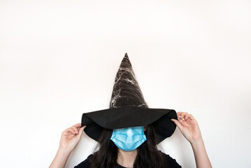 Una chica joven disfrazada para Halloween con un gorro de bruja con arañas y una mascarilla...