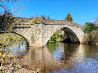 Fototapeta na wymiar Stone built arched bridge over the River Derwent in the town of Froggat in Derbyshire