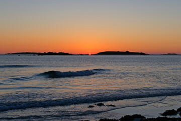 Last of the days sunlight as the sun sinks behind small islands off the beach in Landeda, Brittany
