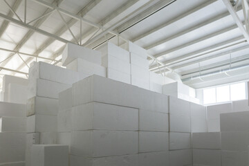 Industrial production of polystyrene foam insulation panels or plates from expanded polystyrene. A large blocks of Styrofoam are stacked in a warehouse. Building materials. - obrazy, fototapety, plakaty