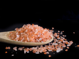 Fototapeta na wymiar Himalayan salt on wooden ladle with black background. Raw food or solt for aroma therapy spa concept.