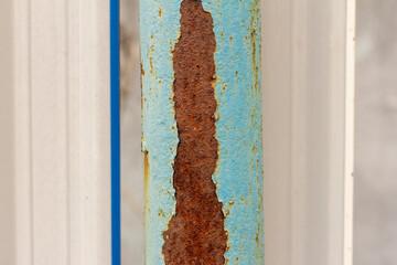 a rusty metal pole with blue paint falling off