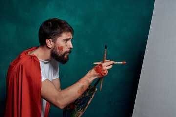 Male artist red cloak drawing easel art green background image