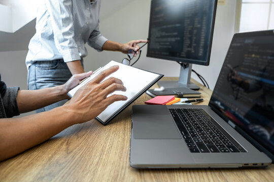 Two professional programmer cooperating and working on web site project in a software developing on desktop computer at company, codes and typing data code, Programming with HTML, PHP and javascript