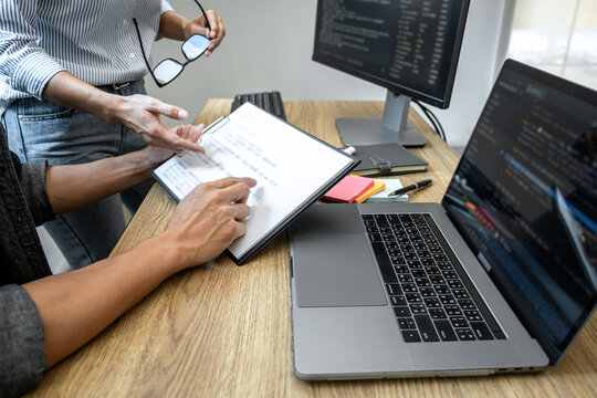 Two professional programmer cooperating and working on web site project in a software developing on desktop computer at company, codes and typing data code, Programming with HTML, PHP and javascript