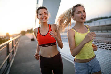 Fit happy friends jogging and running together outdoor in city