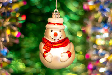 Vintage old Soviet Christmas tree toy (snowman) on the background of a Christmas tree and New Year's multi-colored tinsel.
