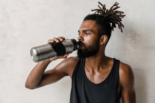 Image of handsome african american sportsman drinking water