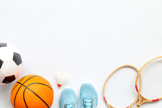 Flat lay of sport balls and rackets on white background. Above view, copy space