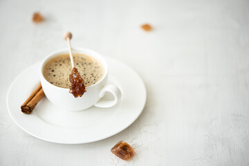 a cup of black coffee with cinnamon and caramelized sugar on a stick