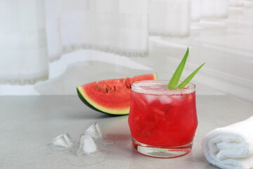 a glass of fresh water melon on the grey table with a slice of water melon near the curtain in the white bedroom during summer holiday in the luxury hotel in Thailand with happy family members