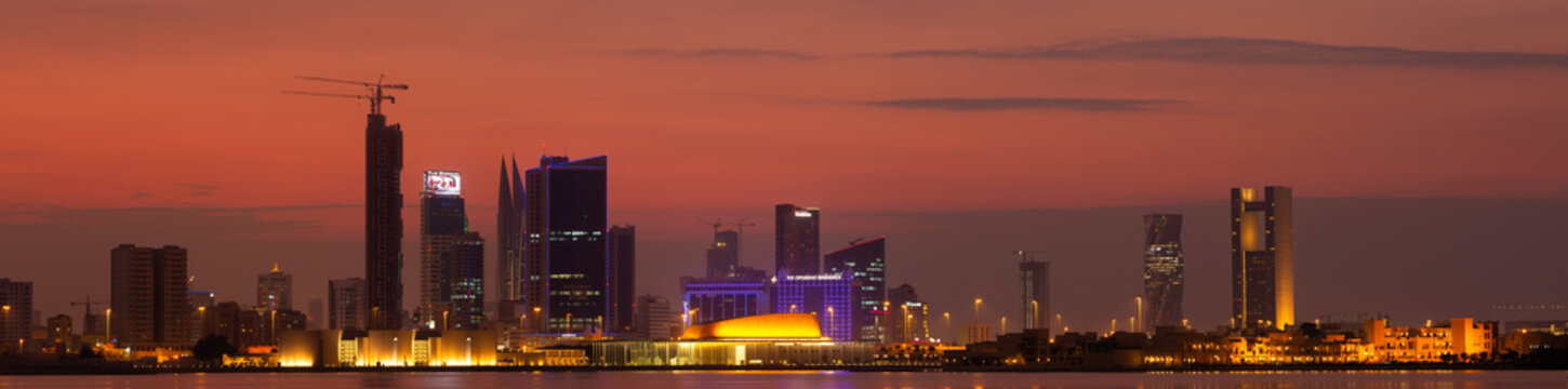MANAMA , BAHRAIN - NOVEMBER 25: A panoramic view of Bahrain skyline with illuminated iconic buildings and dramatic hue in the sky on 25 November, 2019, Manama, Bahrain.