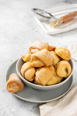 Lots of bagels. Puff pastry in a grey bowl on a light grey table. Cookies close up	