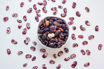 Fototapeta na wymiar Raw red beans in a bowl and on white table surface.