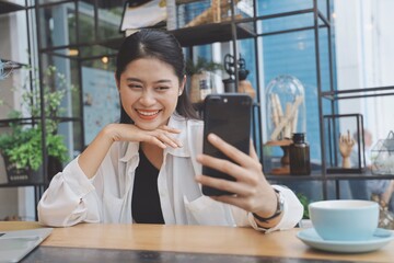 Asian woman using smart phone in coffee shop.