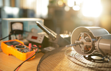 Close-up of motor from home cooling fan lies on a table in workshop