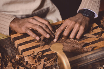 Process of making traditional cigars from tobacco leaves with hands using a mechanical device and...