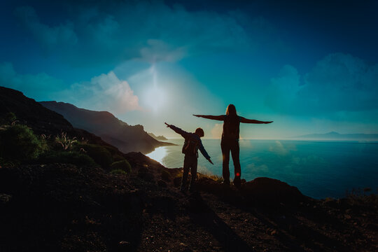 silhouette of happy mother and son travel at sunset mountains