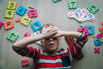 kid tired of learning and playing, boy in stress with toys scattered around