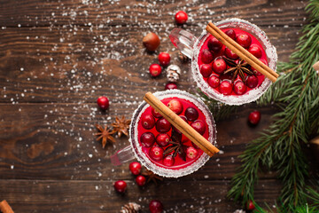 Festive Cranberry drink on Christmas background with fir branches and fresh berries, selective focus. Holiday concept. Dark rustic wooden table, Winter time