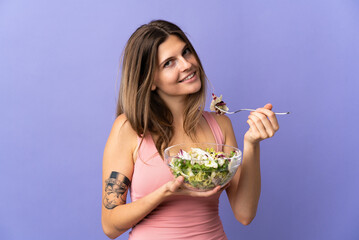 Young slovak woman isolated on purple background holding a bowl of salad with happy expression