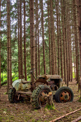 Fototapeta na wymiar abandoned old rusty tractor left in a pine forest