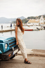 Cheerful girl standing near car outside. Traveler content.