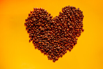 coffee seeds in shape of heart on yellow background