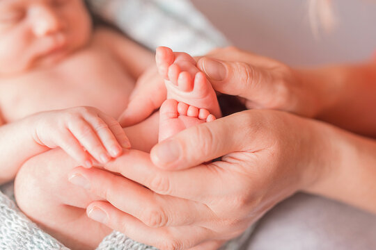 Beautiful conceptual image of Maternity. Little baby feet in mother hands, closeup
