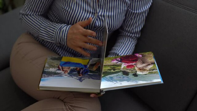 close up. a woman flips through a photo book from a family photo shoot in the garden. beautiful and convenient storage of photos. memory of an important period.