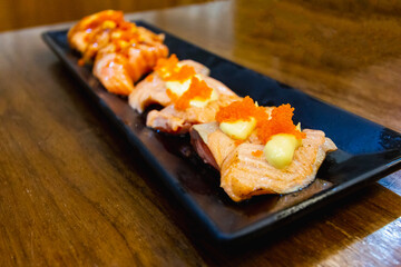 salmon grilled with cheese over Shrimp Roe on top in black bowl of Japanese food at restaurant