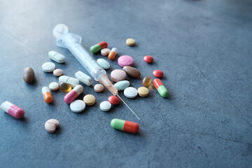 syringe and pills on dark background, close up 