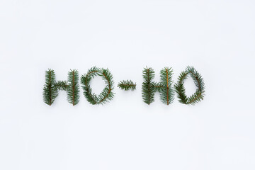 Words Ho Ho made of fir branches on white background. Minimal Christmas and New Year concept. Top view.
