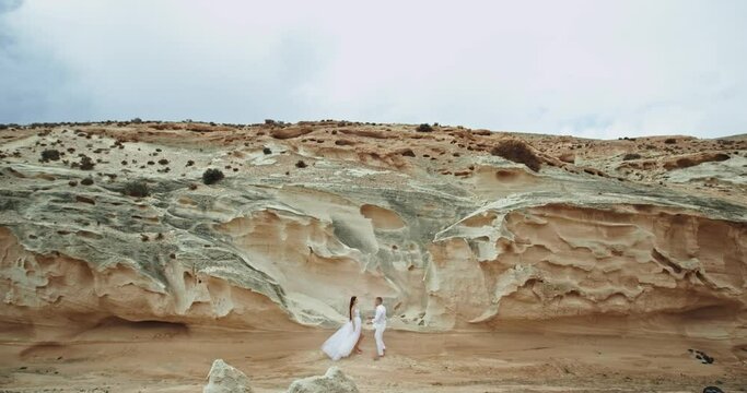 In amazing landscape view they hugging each other and feeling romantic together background big cliffs and rocks