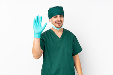 Surgeon in green uniform isolated on isolated white background saluting with hand with happy expression