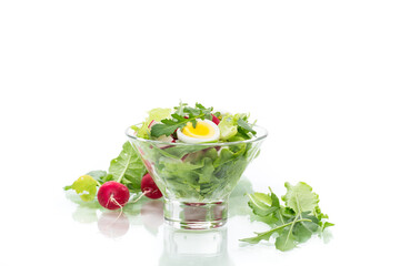 spring salad with arugula, boiled eggs, fresh radish, salad leaves in a glass bowl
