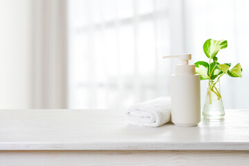 Spa towel, soap dispenser and plant leaves on window background