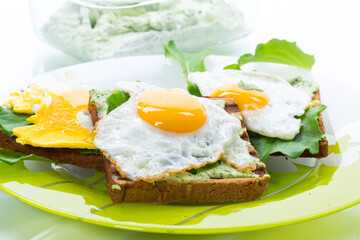 fried toast with cheese spread of arugula and fried egg in a plate