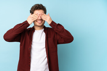 Young caucasian man isolated background covering eyes by hands and smiling