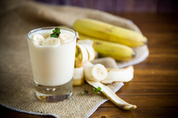 tasty homemade yogurt with bananas in a glass on a wooden table