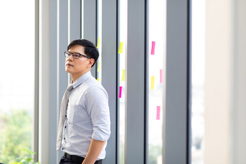 Fototapeta premium Portrait of successful smiling Asian businessman executive stylish. Close up face of happy successful business man standing by windows.