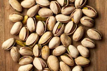 Top view of pistachios on a wooden board on a dark background.