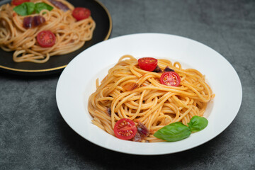 Delicious tomato and mushroom spaghetti on a white plate, spaghetti on a black plate
