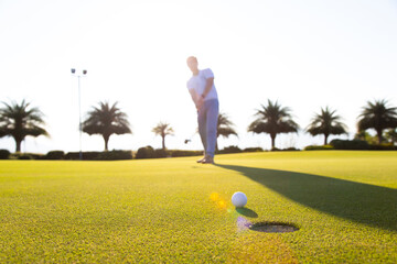 Golf club and ball in grass at the Golf course. White Golf ball on Green field golf course in...