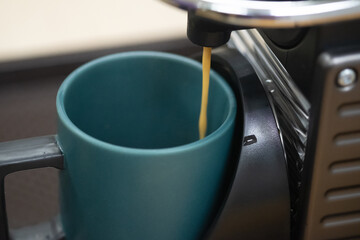 Coffee machine pouring coffee into green ceramic mug