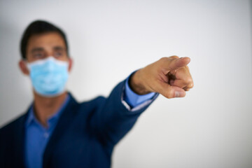 An adult man with a mask pointing his finger forward.