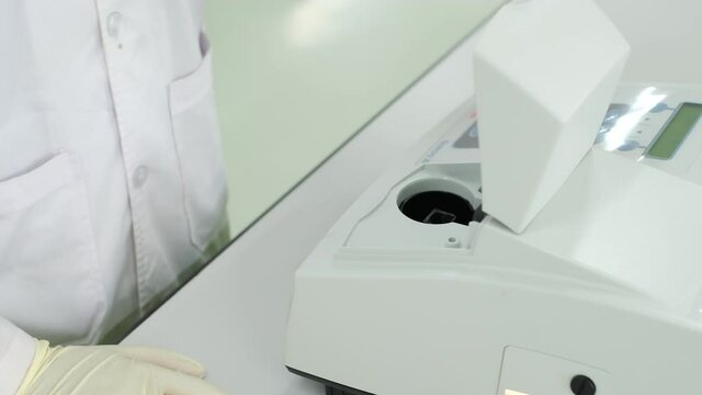 Young Asia chemical science put Quartz cuvette contains a pink solution sample into a spectrophotometer (UV). Looking and check the sample before put into the machine. Education concept.