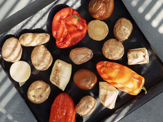 Baked vegetables on a baking sheet, potatoes, tomatoes, bell peppers, zucchini. Top view.