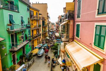 Fototapeta na wymiar Overlooking the beautiful and busy road Via Renato Birolli with its colourful houses on each side in Manarola, the second-smallest of the famous Cinque Terre towns in Liguria, Italy.