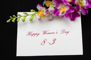 Happy Womans Day March 8th written on white card with red roses